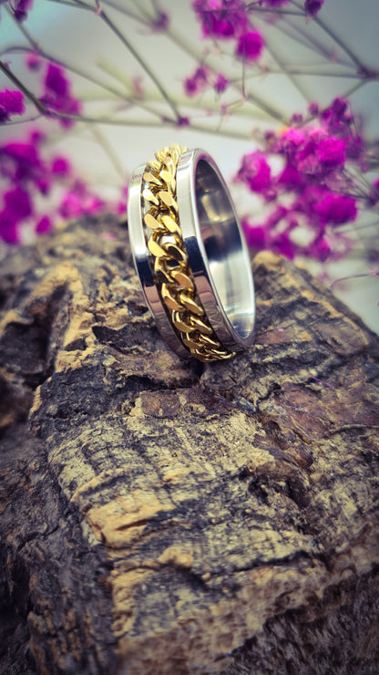 Anillo tipo alianza de matrimonio o pareja en acero inoxidable con cadena dorada y ancho de 8mm. Se incluye grabado de nombres y fecha importante gratis. Posa sobre tronco.