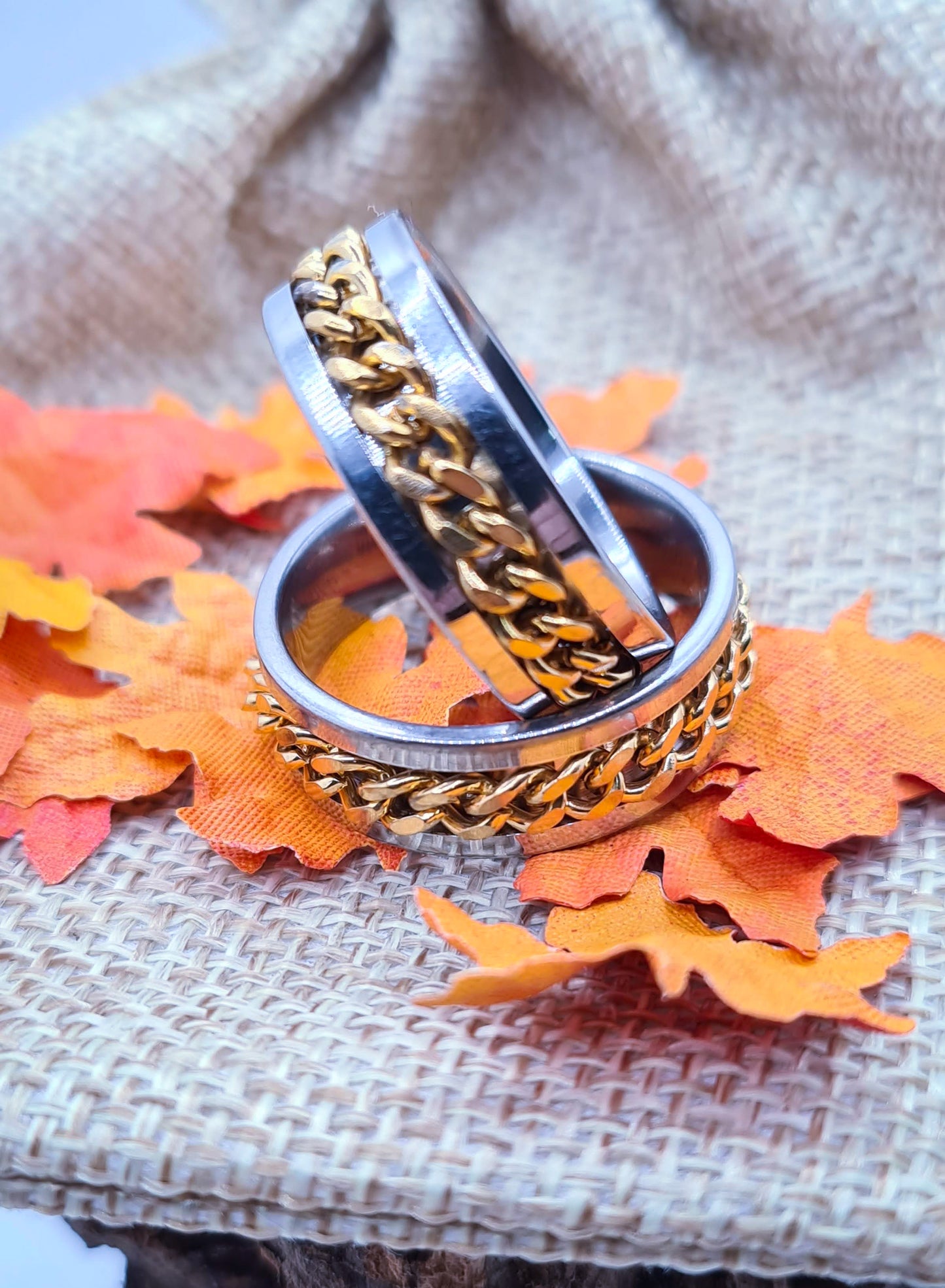Dos Anillos tipo alianza de matrimonio o pareja en acero inoxidable con cadena dorada y ancho de 8mm. Se incluye grabado de nombres y fecha importante gratis. Posan sobre saco.