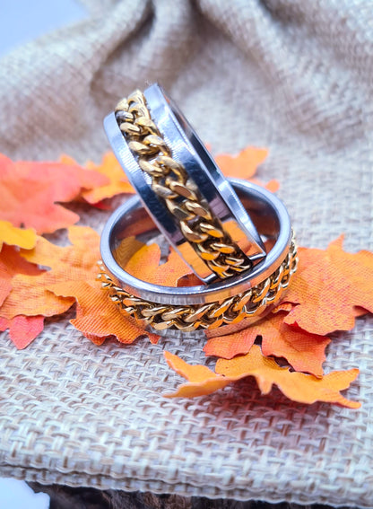 Dos Anillos tipo alianza de matrimonio o pareja en acero inoxidable con cadena dorada y ancho de 8mm. Se incluye grabado de nombres y fecha importante gratis. Posan sobre saco.