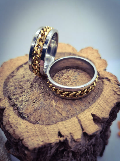 Dos Anillos tipo alianza de matrimonio o pareja en acero inoxidable con cadena dorada y ancho de 8mm. Se incluye grabado de nombres y fecha importante gratis. Posan sobre tronco.