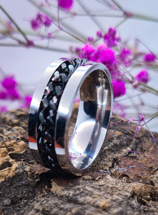 Anillo tipo alianza de matrimonio o pareja en acero inoxidable con Cadena negra y ancho de 6mm. Se incluye grabado de nombres y fecha importante gratis. Posa sobre tronco.
