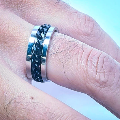 Anillo tipo alianza de matrimonio o pareja en acero inoxidable con Cadena negra y ancho de 6mm. Se incluye grabado de nombres y fecha importante gratis. Posa sobre mano de hombre.