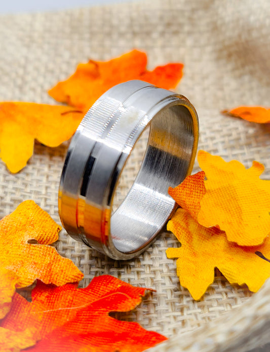 Anillo tipo alianza de matrimonio o pareja en acero inoxidable biselado y ancho de 8mm. Se incluye grabado de nombres y fecha importante gratis. Posa sobre saco.