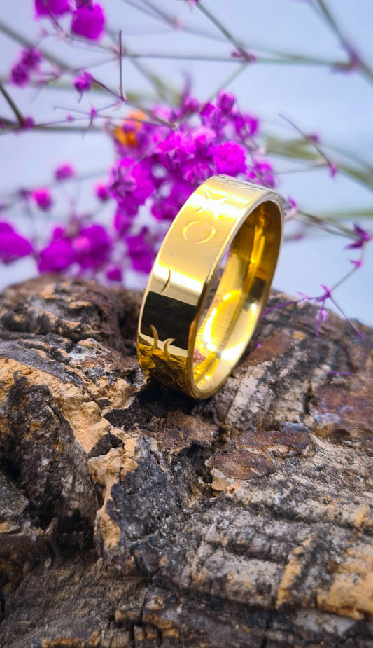 Anillo tipo alianza de matrimonio o pareja en acero inoxidable dorado y ancho de 6mm. Se incluye grabado de nombres y fecha importante gratis. Posa sobre tronco.