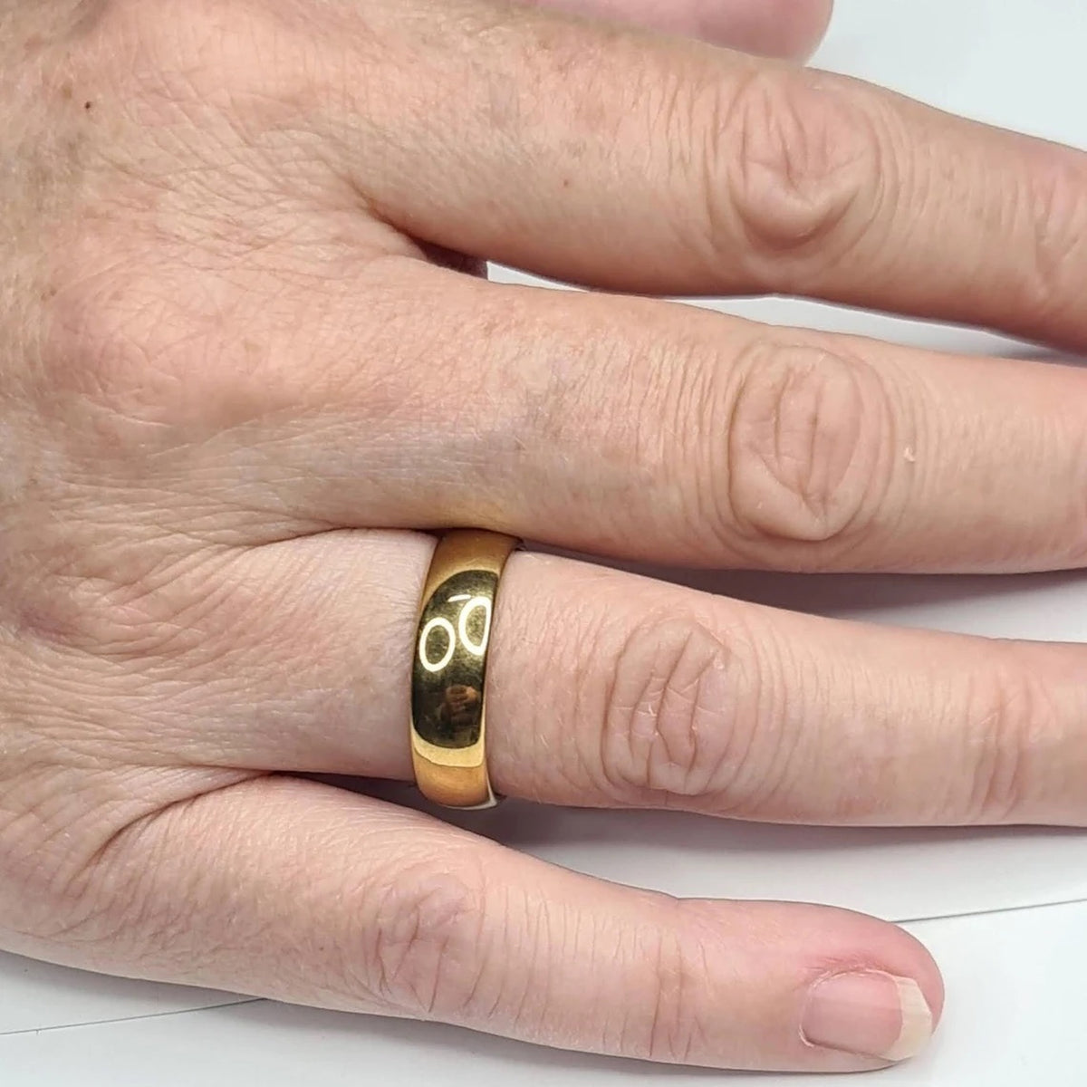 Alianza dorada de 6 mm puesta en una mano femenina.
