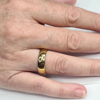 Alianza dorada de 6 mm puesta en una mano femenina.