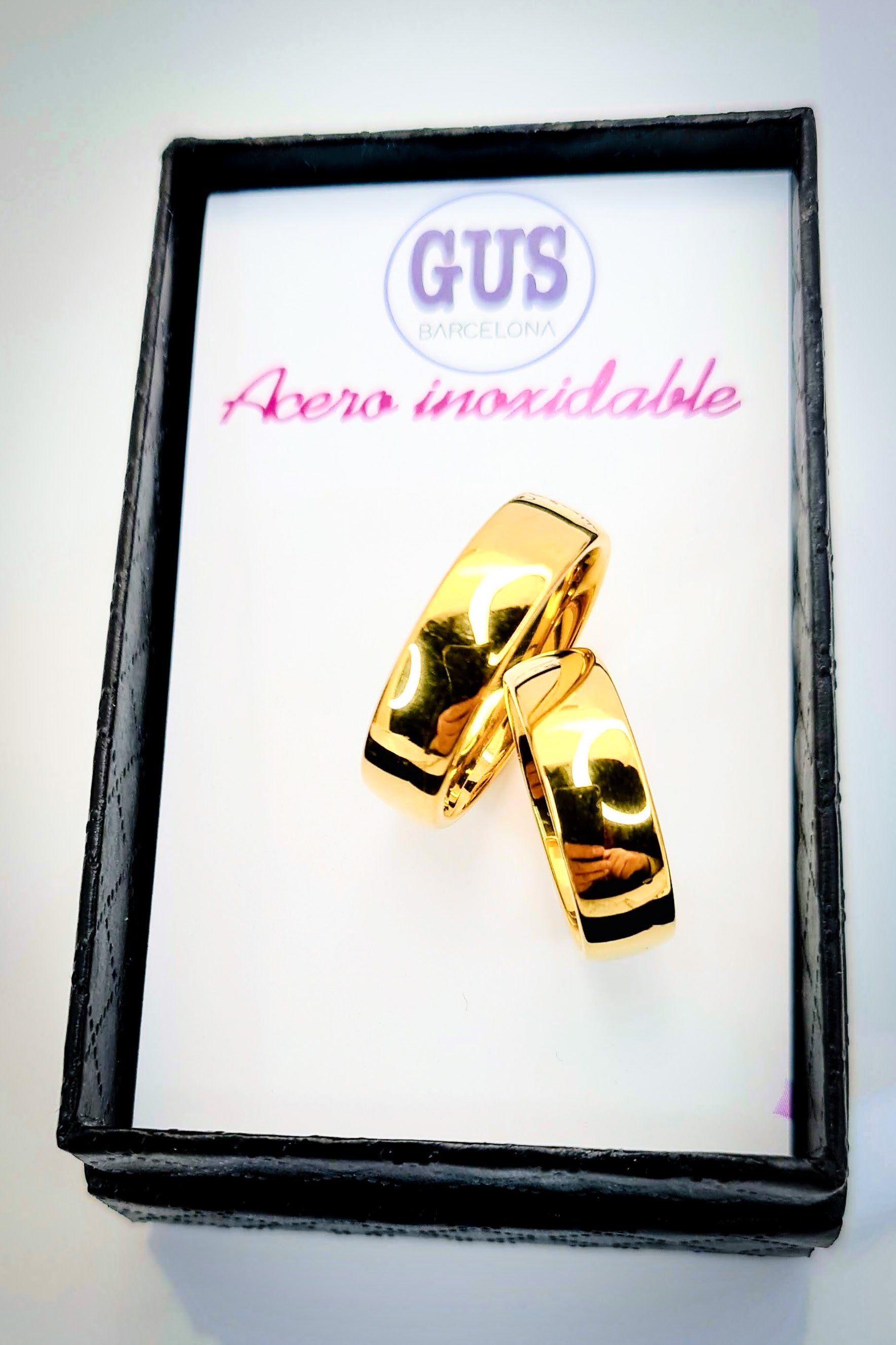 Anillo tipo alianza de matrimonio o pareja en acero inoxidable en color dorado y ancho de 6mm. Se incluye grabado de nombres y fecha importante gratis. Los anillos están sobre una caja.