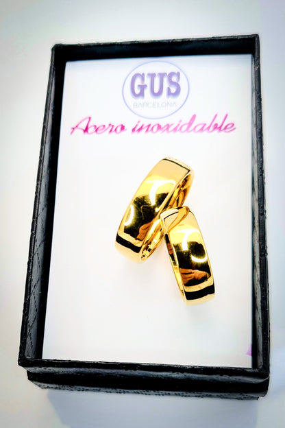 Anillo tipo alianza de matrimonio o pareja en acero inoxidable en color dorado y ancho de 6mm. Se incluye grabado de nombres y fecha importante gratis. Los anillos están sobre una caja.