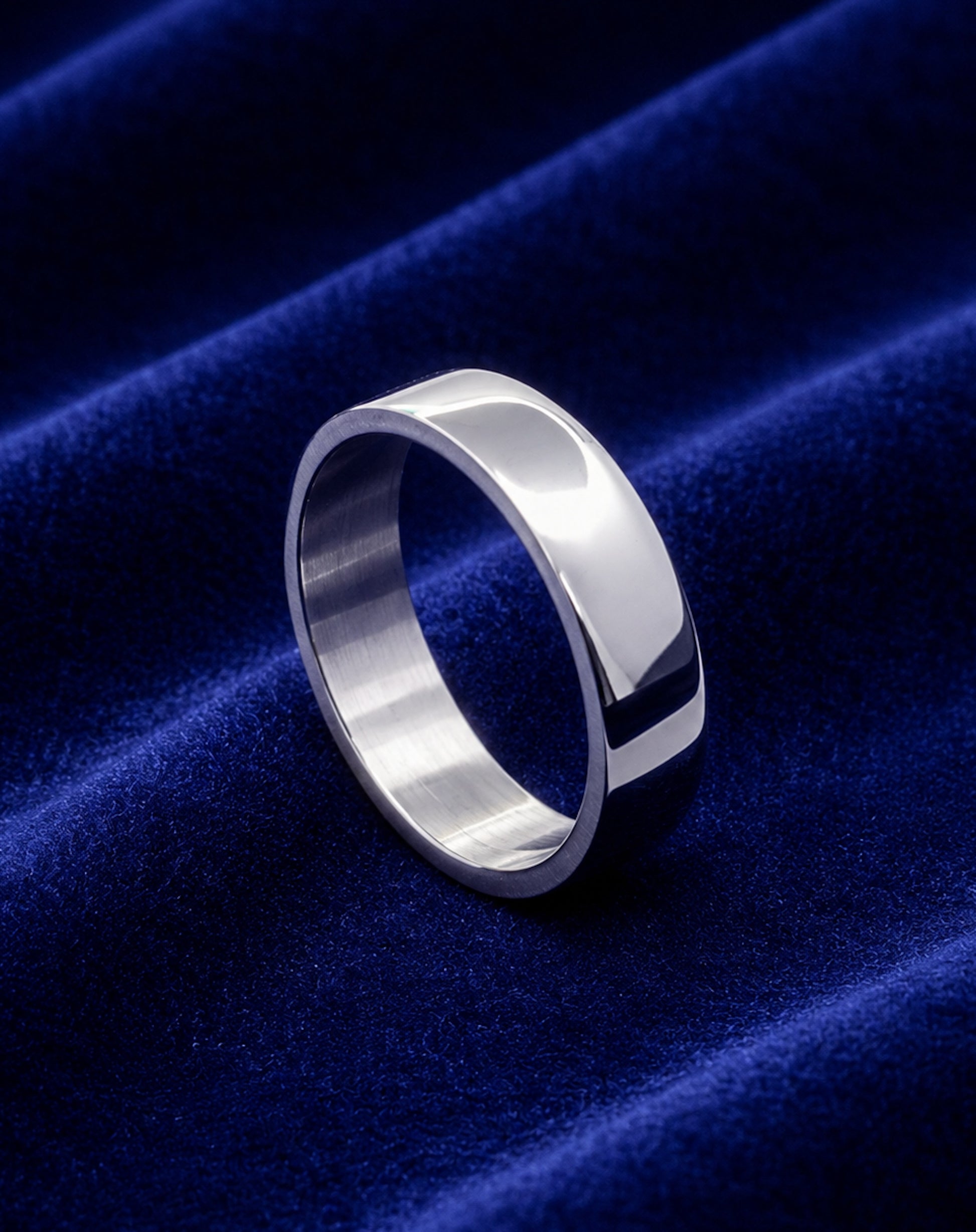 Alianza plana de acero inoxidable de 6 mm sobre terciopelo azul.