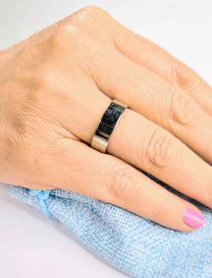 Primer plano de anillo plano de acero inoxidable en mano femenina.