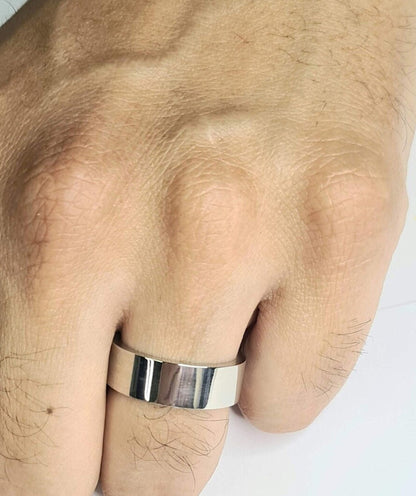 Primer plano de alianza plana plateada de 8 mm en mano masculina.