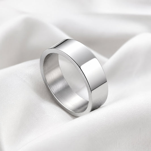 Anillo plano plateado de acero inoxidable sobre tela blanca satinada.