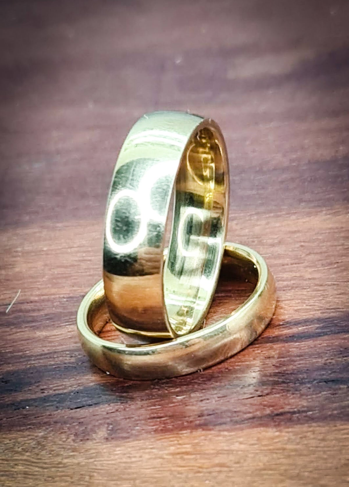 Pack de dos anillos dorados de acero inoxidable sobre superficie de madera.