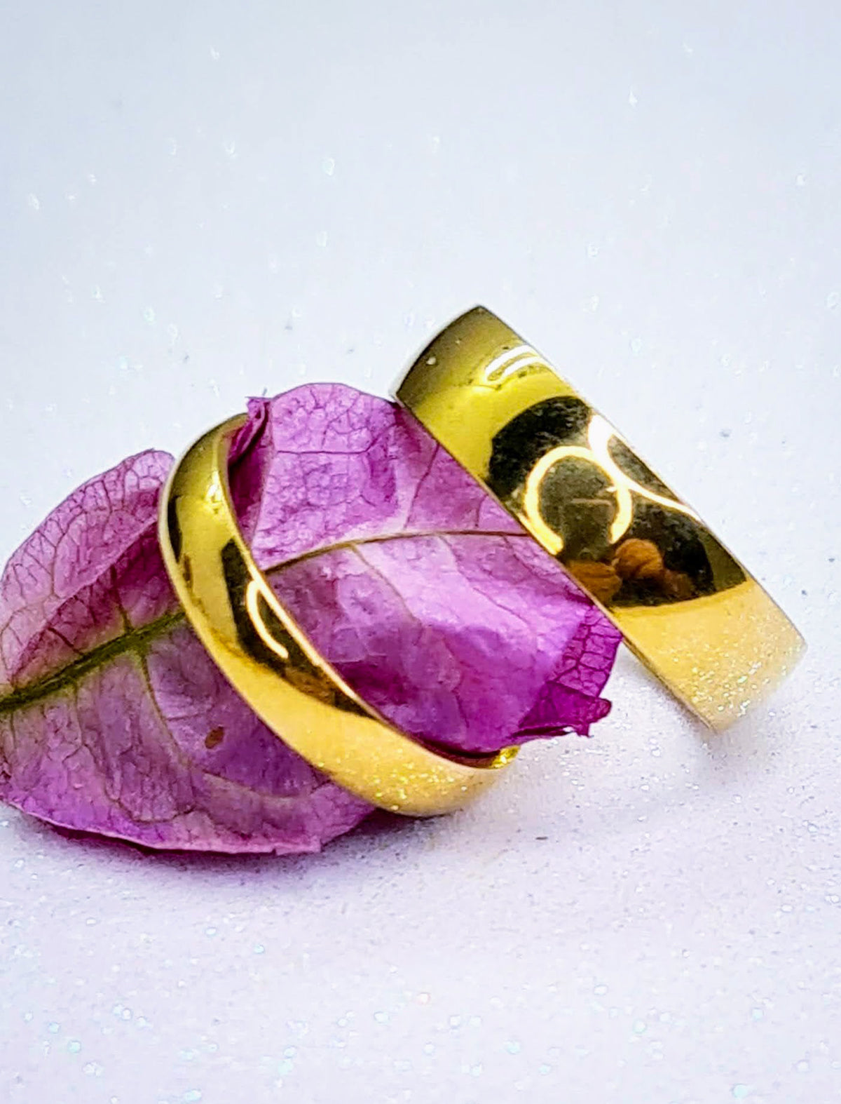 Alianzas doradas para pareja con pétalos rosas.