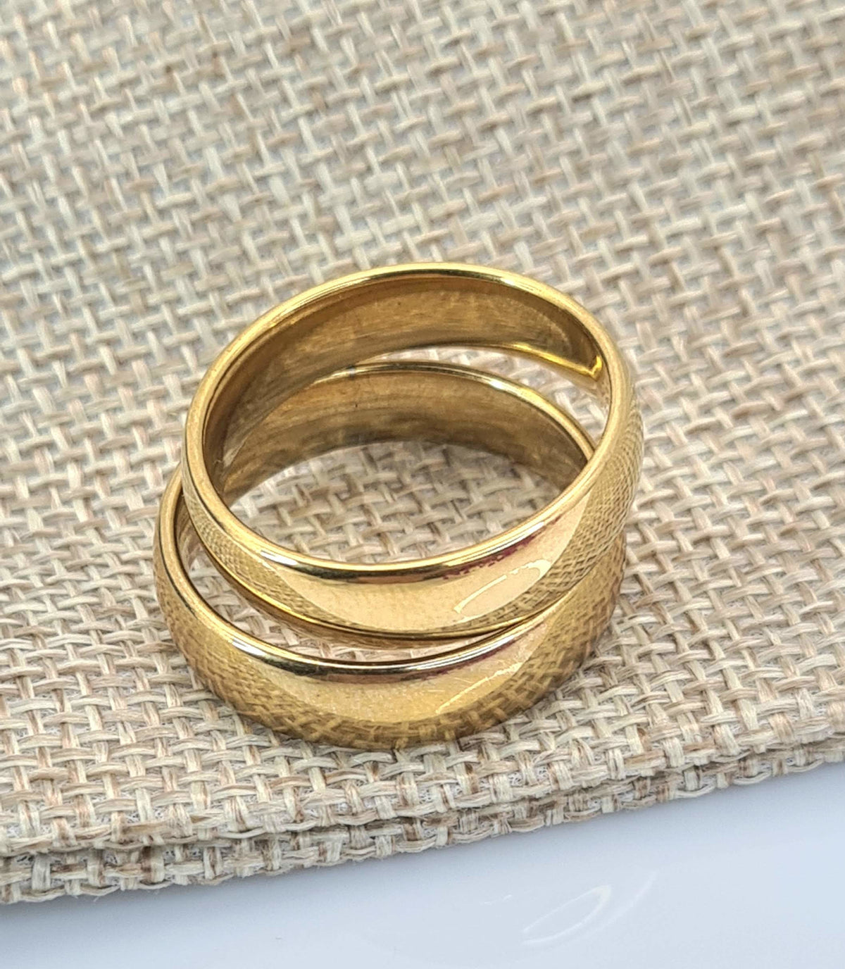 Set de anillos media caña dorados sobre tejido beige.
