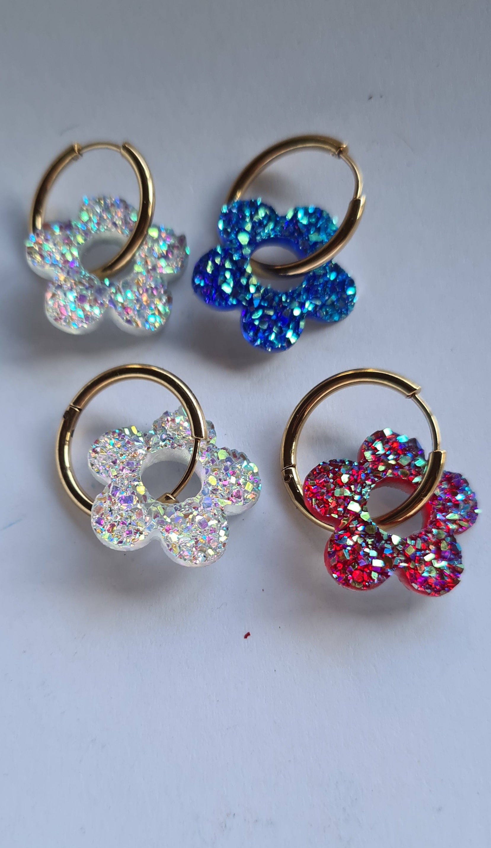 Aros acero inoxidable dorados con Flor de Acrílico Brillante para mujer. Fondo blanco.