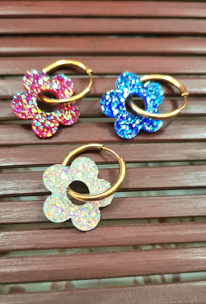 Aros acero inoxidable dorados con Flor de Acrílico Brillante para mujer. Fondo rejilla de Madera.