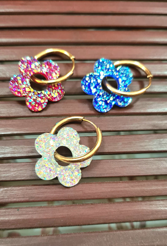 Aros acero inoxidable dorados con Flor de Acrílico Brillante para mujer. Fondo rejilla de Madera.