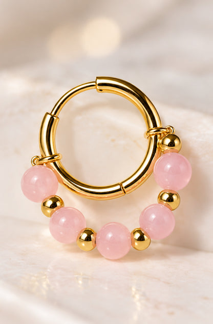 Detalle de aro dorado con cuarzo rosa y pequeñas cuentas doradas.