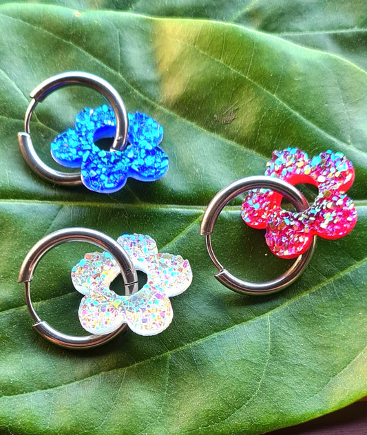 Aros acero inoxidable plateados con Flor de Acrílico Brillante para mujer. Fondo hoja verde.