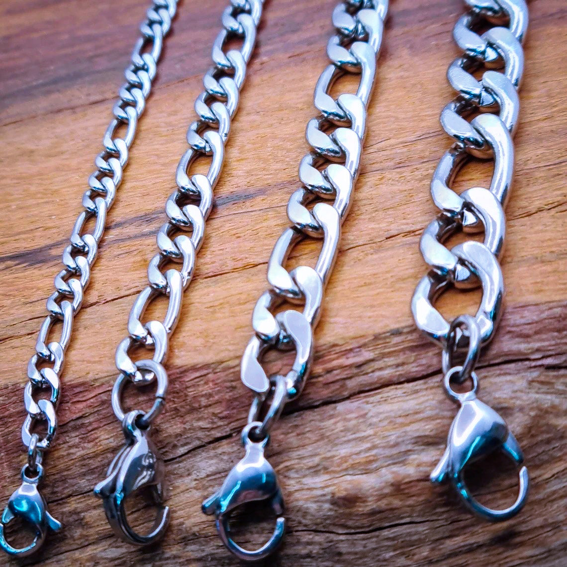 4 Cadenas acero inoxidable modelo Fígaro, 4 anchos. Posa sobre tabla de madera.