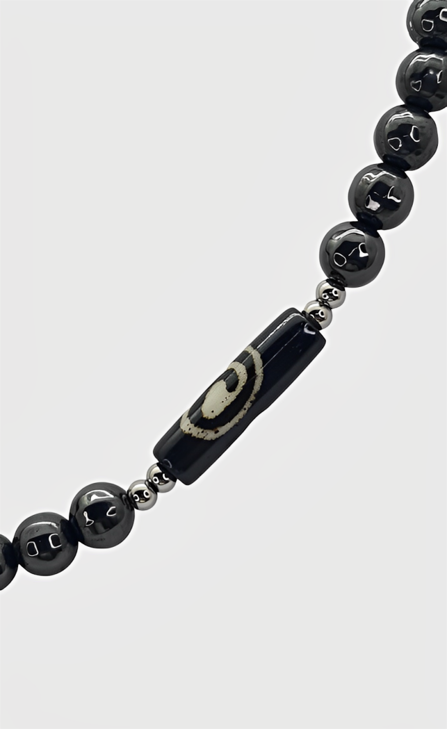 Collar para hombres cuentas de Hematite, acero y Hueso de Yak. Posa sobre fondo blanco.