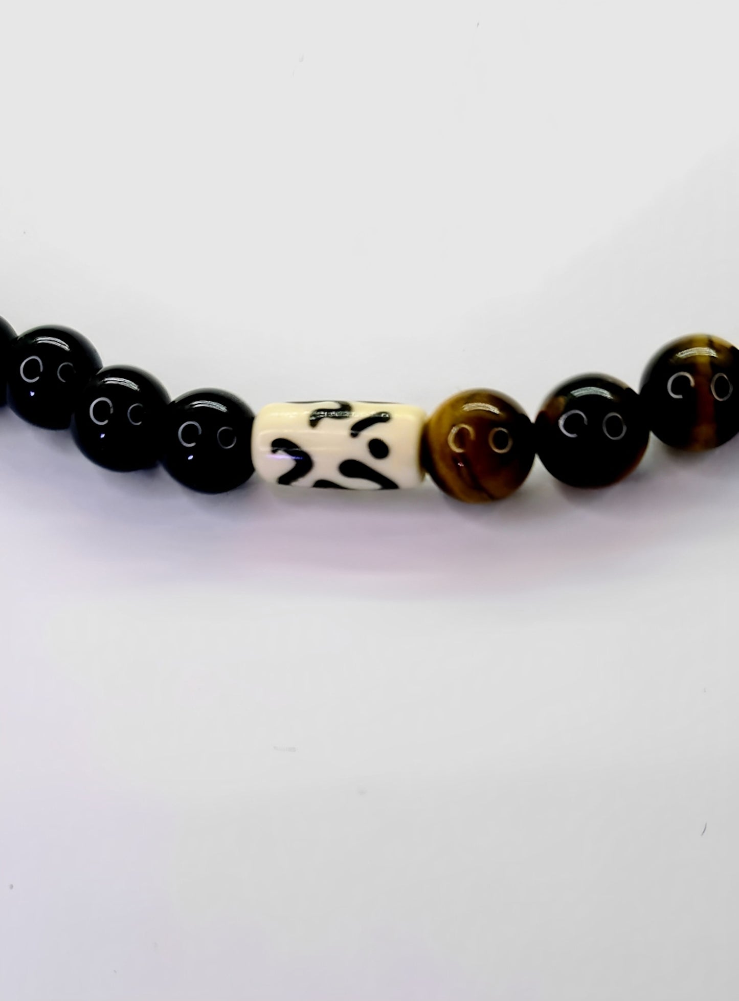 Collar para hombres con cuentas de Ojo de Tigre, Ónix y Hueso de Yak. Posa sobre fondo blanco.
