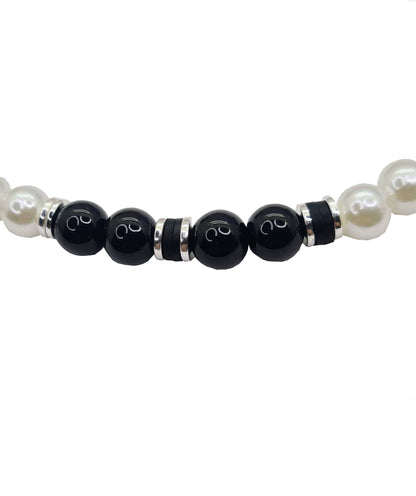Collar unisex cuentas de Perlas, Discos de Arcilla y Acero, y Ónix. Posa sobre fondo blanco.