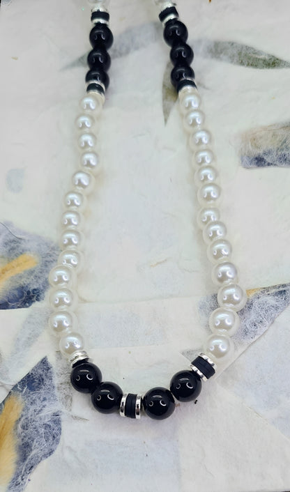 Collar unisex cuentas de Perlas, Discos de Arcilla y Acero, y Ónix. Posa sobre papel.