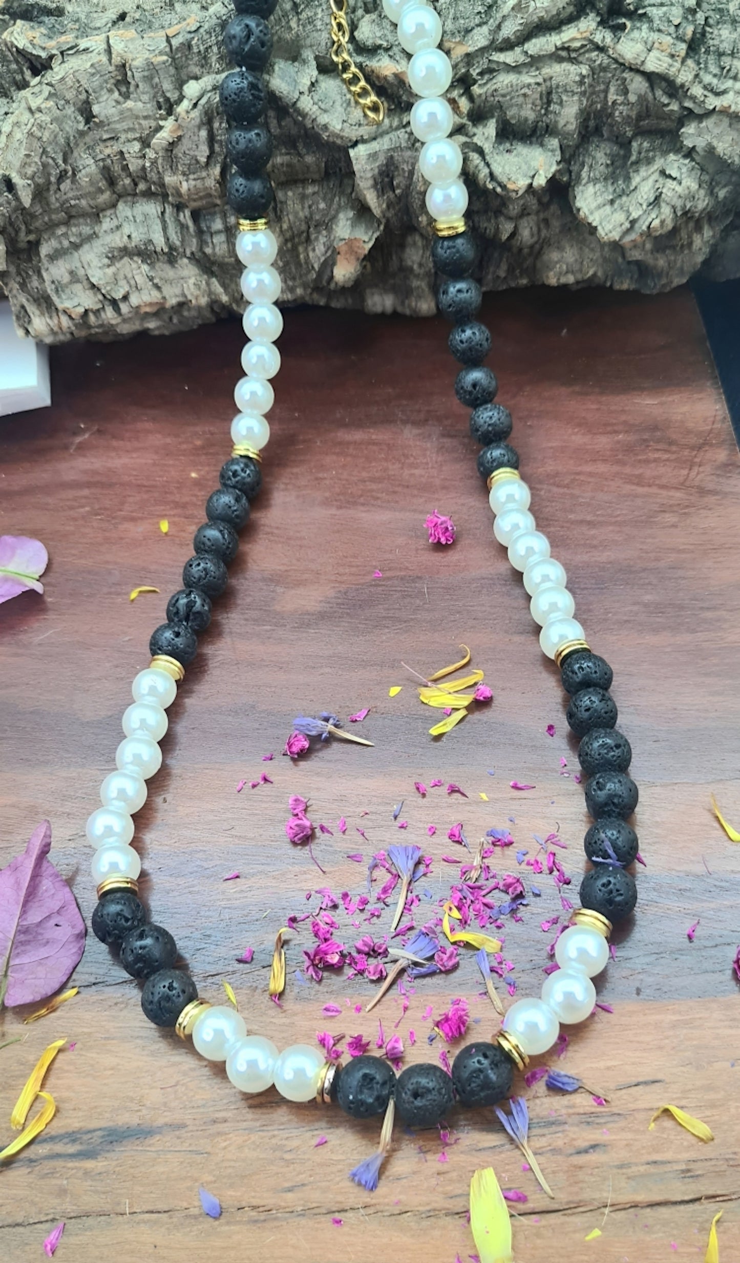 Collar unisex cuentas de Perlas, acero y Lava volcánica negra. Posa sobre madera.