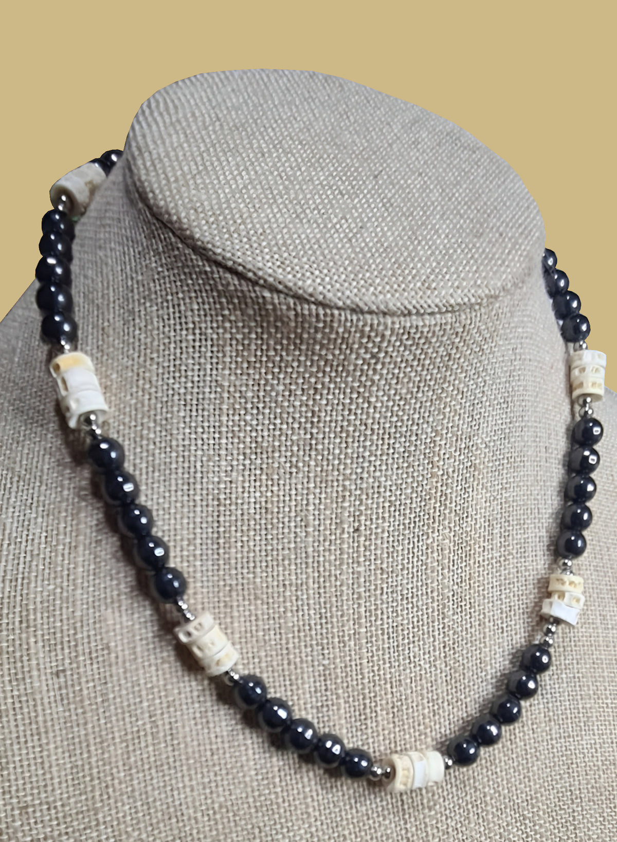 Collar de hematita, hueso de pescado y acero inoxidable presentado sobre busto.