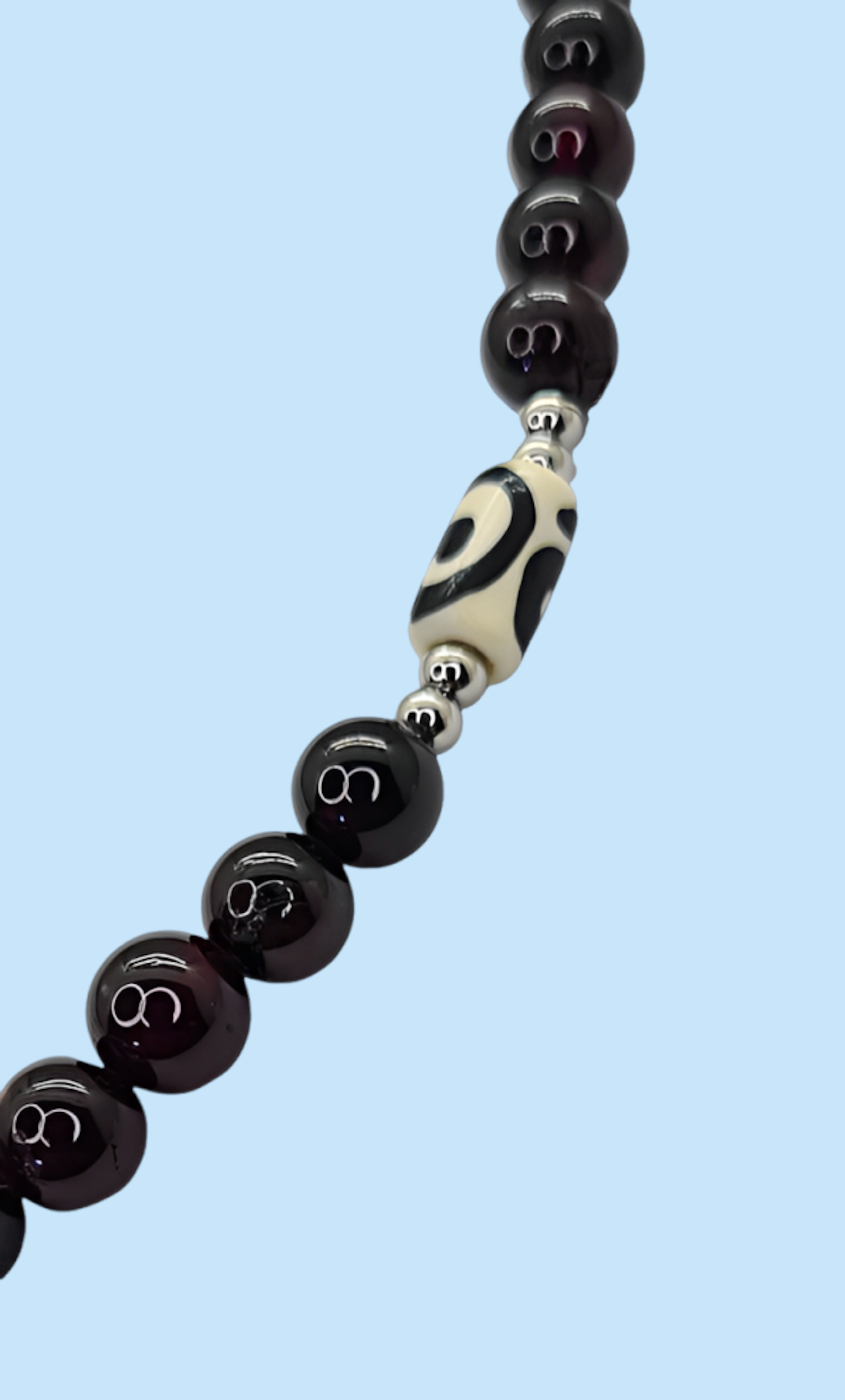 Collar para Hombre con cuentas de Granate y Hueso de Yak. Posa sobre fondo celeste.
