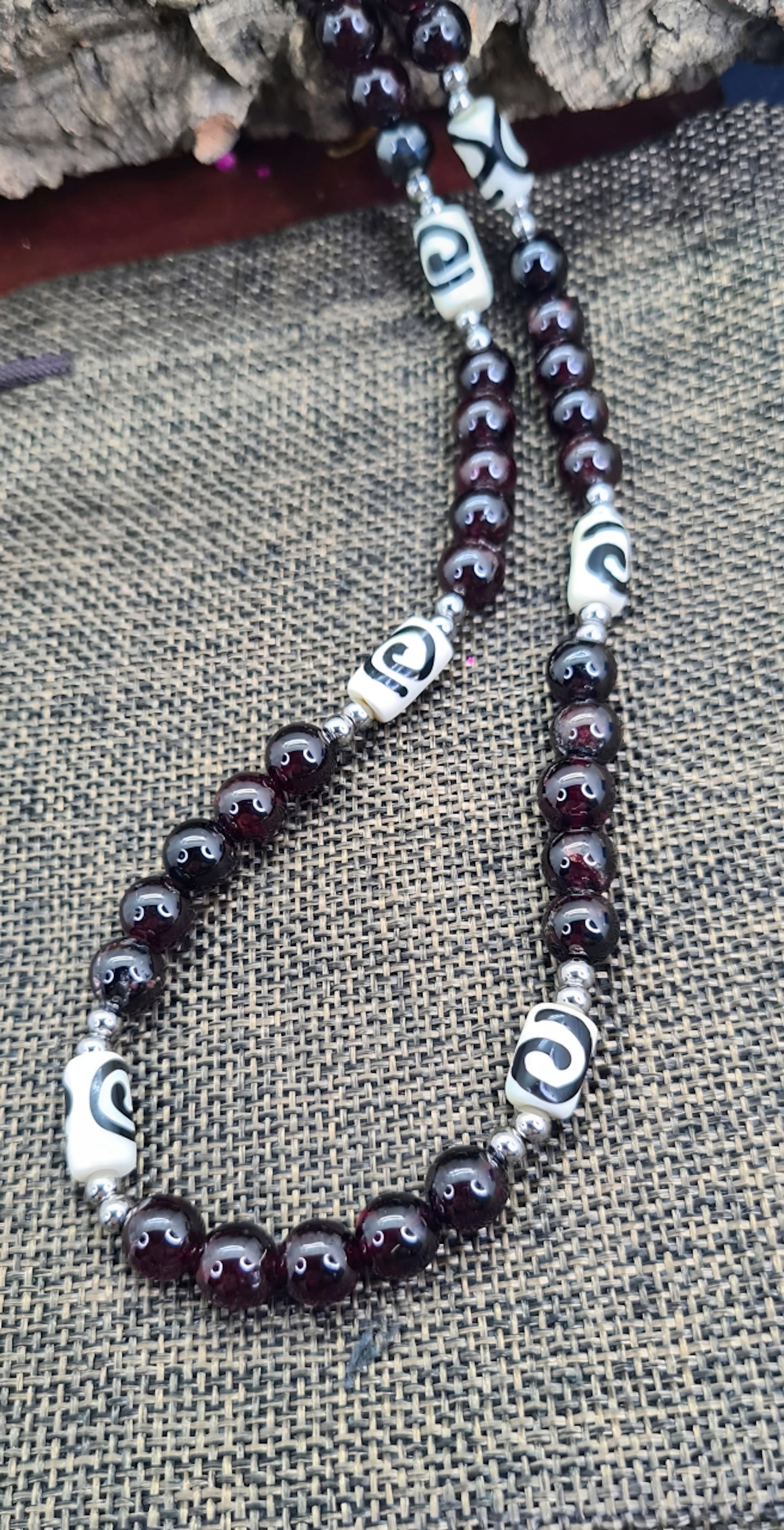 Collar para Hombre con cuentas de Granate y Hueso de Yak. Posa sobre saquito.