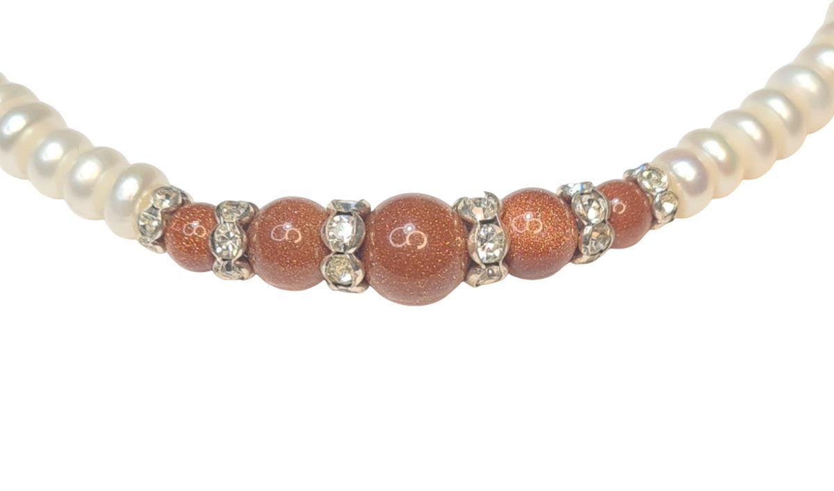 Collar de perlas con centro de aventurina naranja y separadores brillantes.