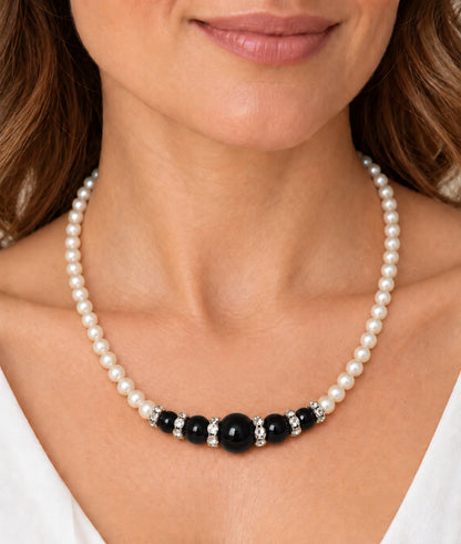 Mujer llevando collar de perlas con composición central de ónix negro.