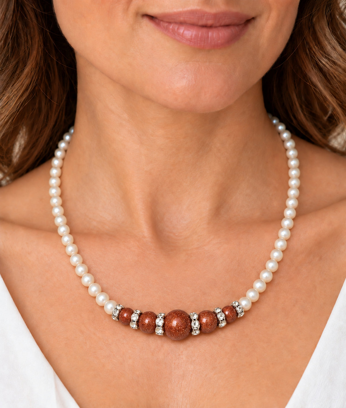 Mujer llevando collar de perlas con composición central de aventurina naranja.