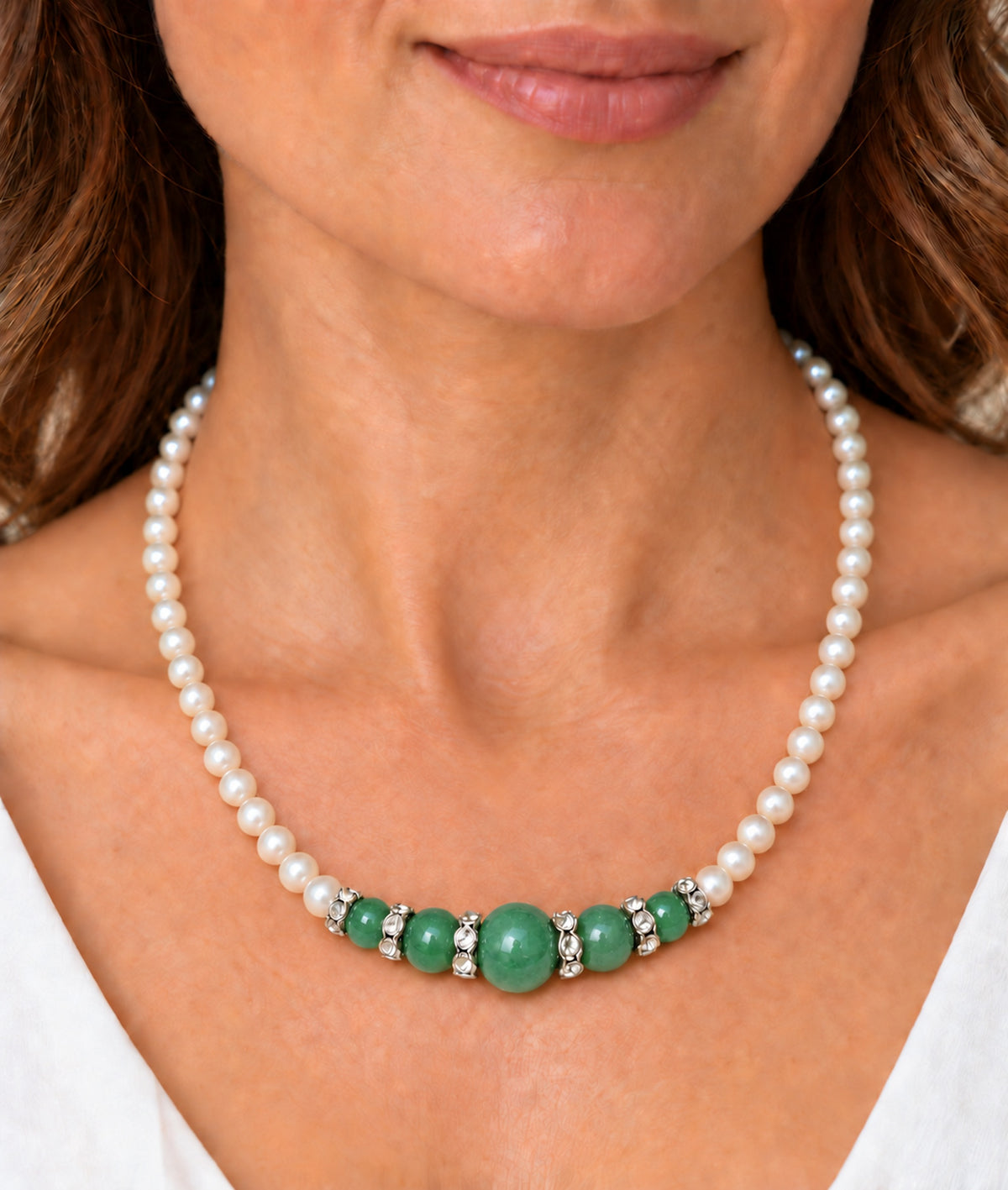 Mujer llevando collar de perlas con composición central de jade verde.