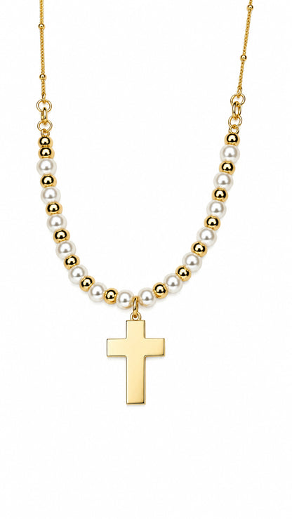 Collar con cruz dorada, perlas blancas y detalles de acero dorado sobre fondo blanco.