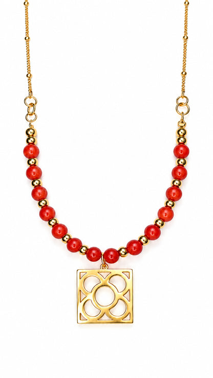 Collar Flor de Barcelona dorado con cuentas de coral manzana rojo sobre fondo blanco.
