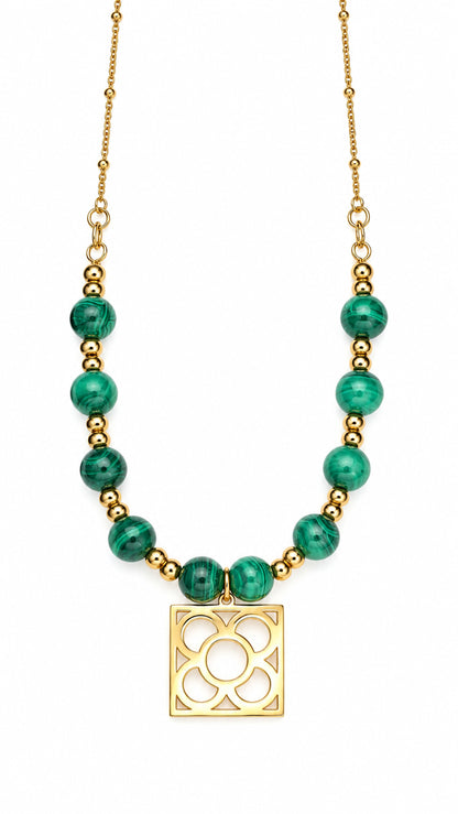 Collar Flor de Barcelona dorado con cuentas de malaquita verde sobre fondo blanco.