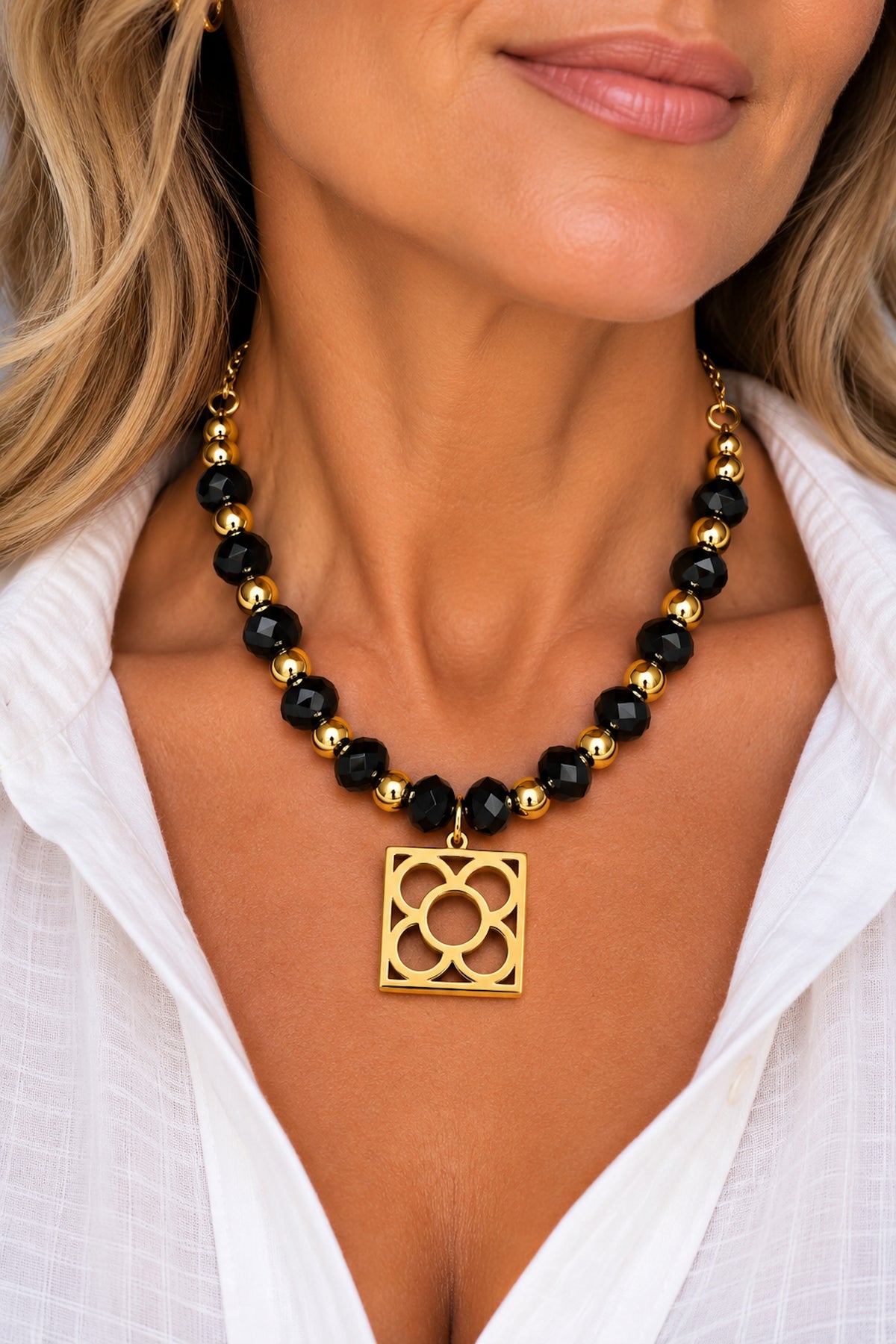 Collar Flor de Barcelona con ónix negro llevado por una mujer con camisa blanca.