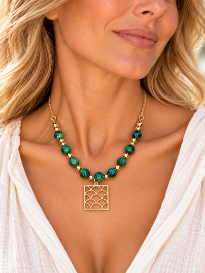Collar de malaquita con colgante dorado de ondas llevado por una mujer.
