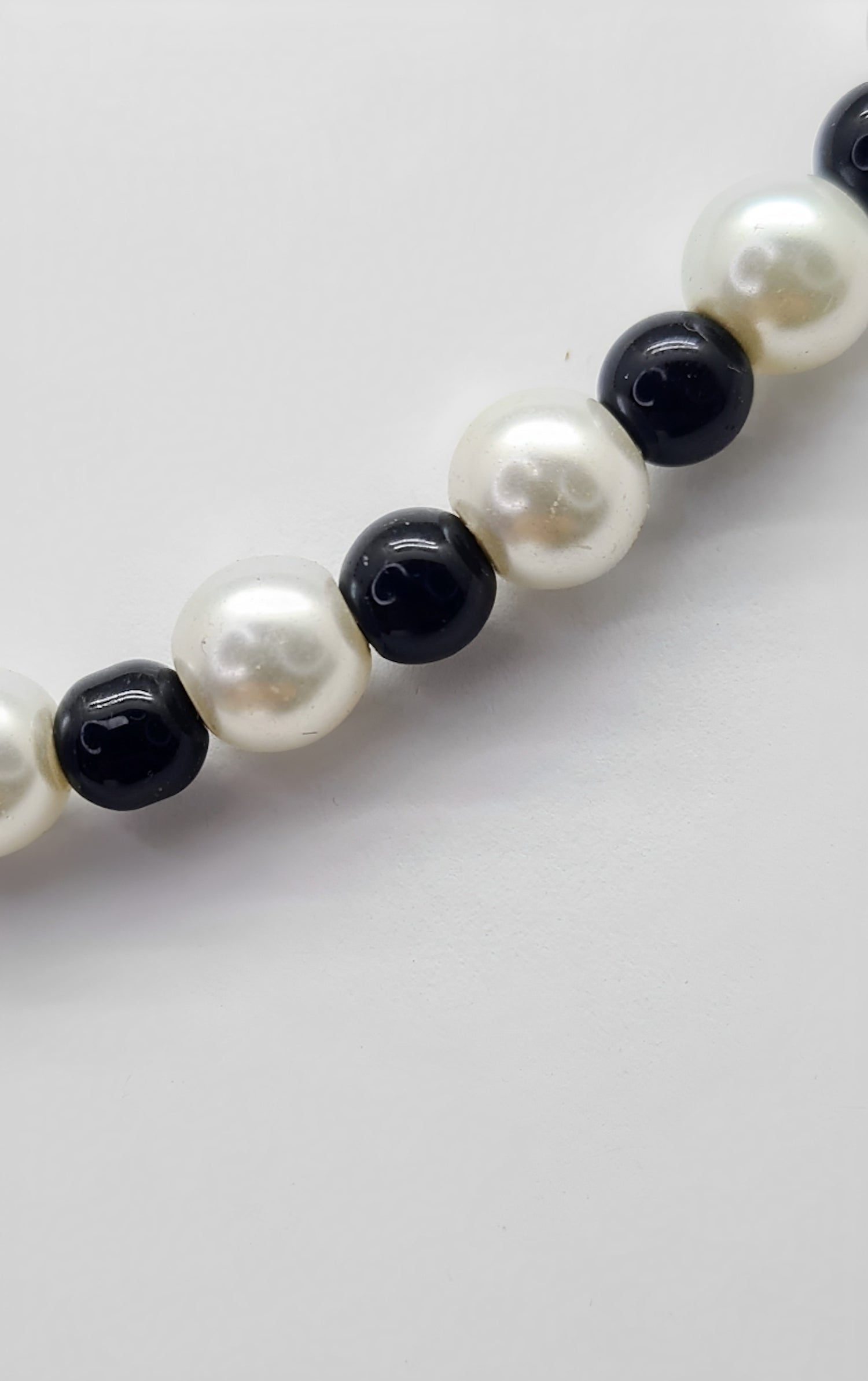 Collar Unisex de cuentas de Ónix y Perlas. Posa sobre fondo blanco.