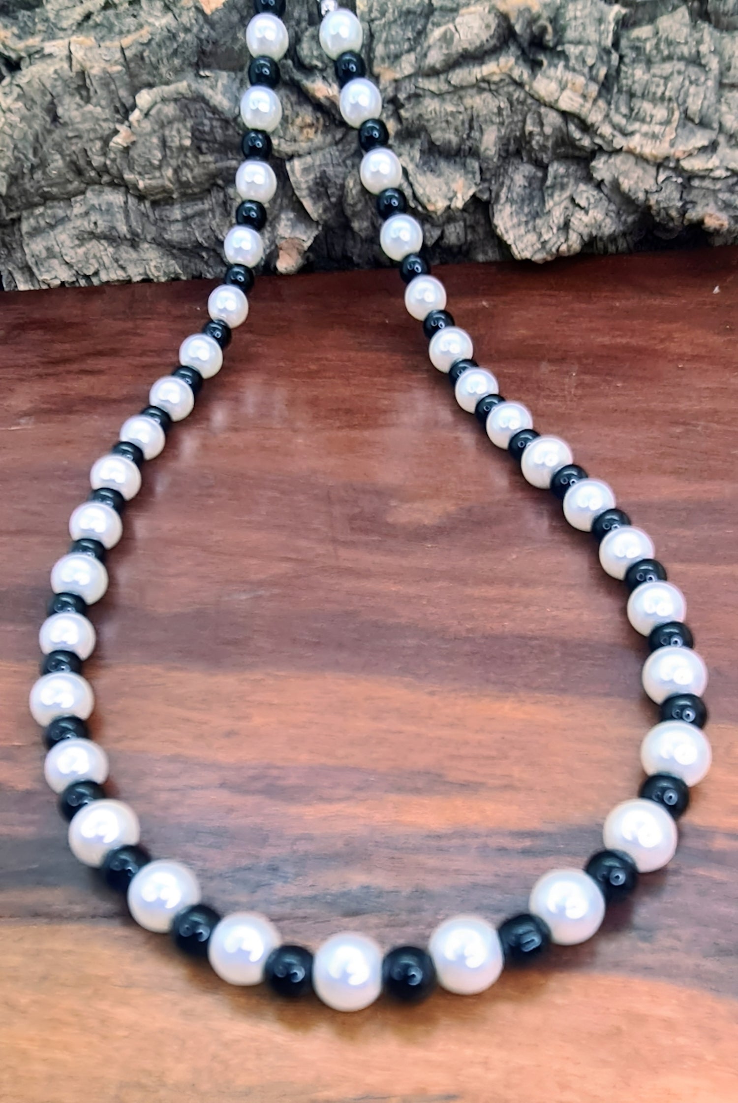 Collar Unisex de cuentas de Ónix y Perlas. Posa sobre madera.