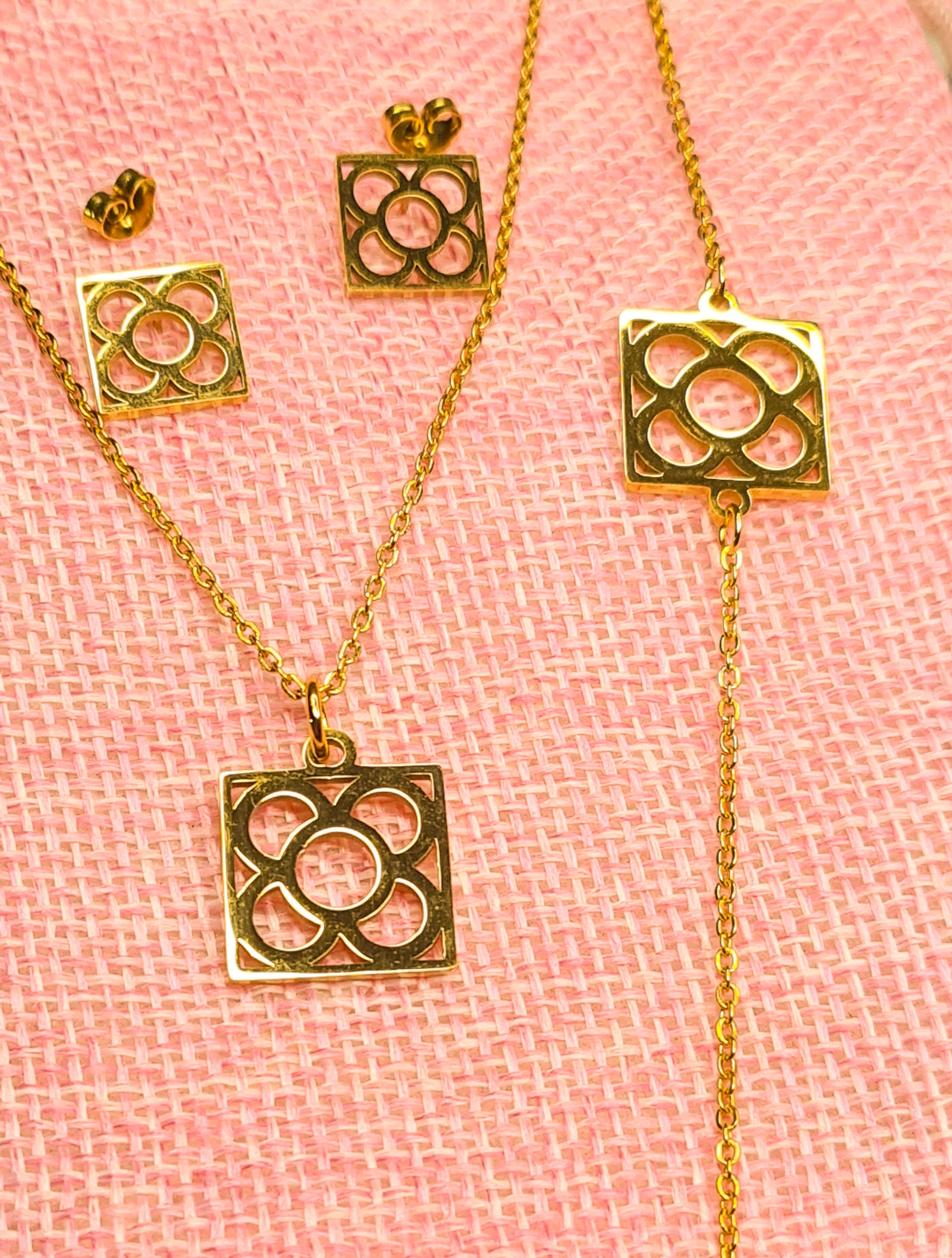 Conjunto Flor de Barcelona Acero Inoxidable dorado para mujer. Posa sobre saquito de arpillera.