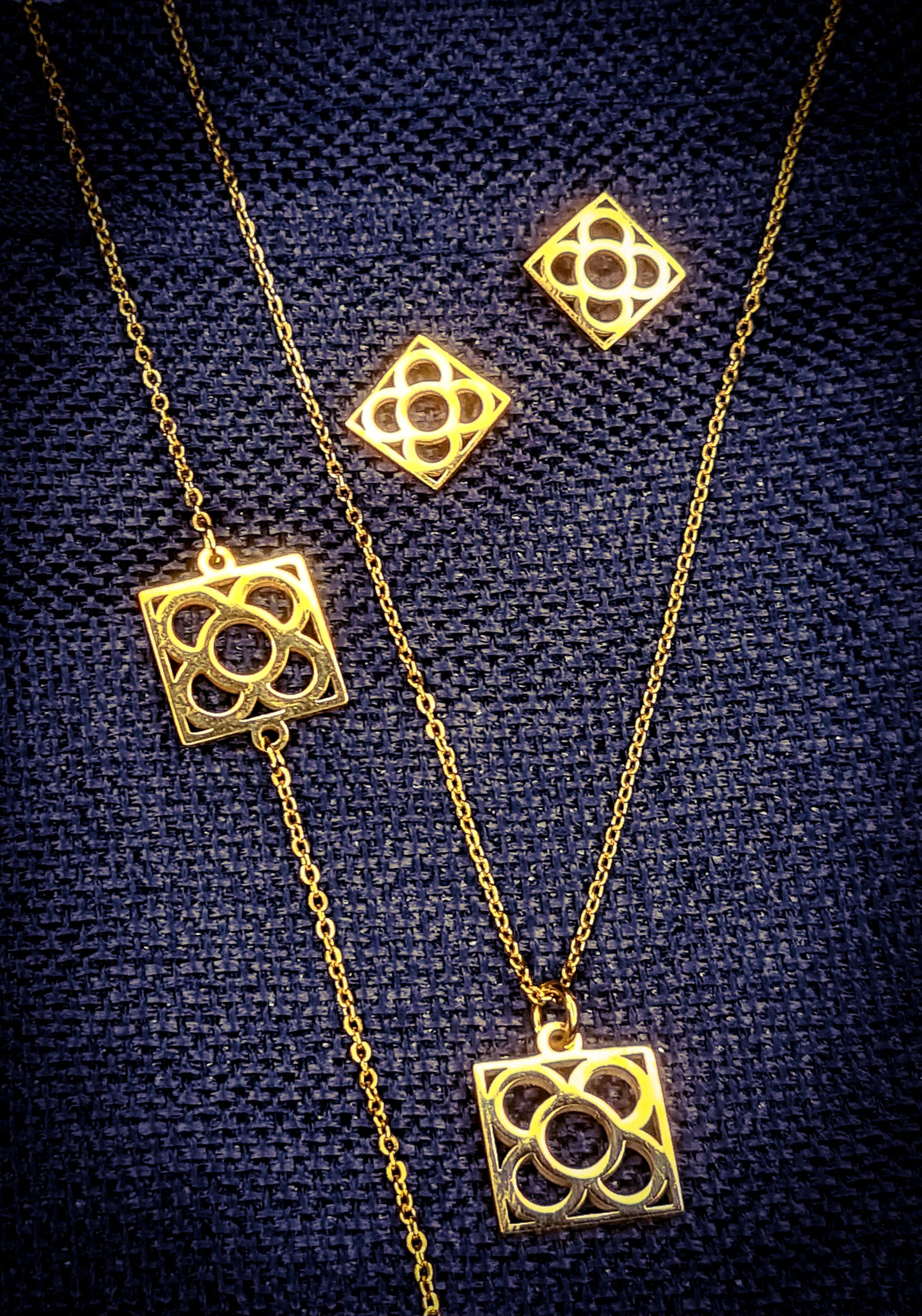 Conjunto Flor de Barcelona Acero Inoxidable dorado para mujer. Posa sobre saquito de arpillera.