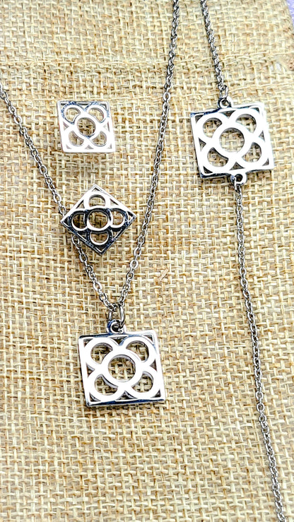 Conjunto Flor de Barcelona Acero Inoxidable para mujer. Posa sobre saquito de arpillera.