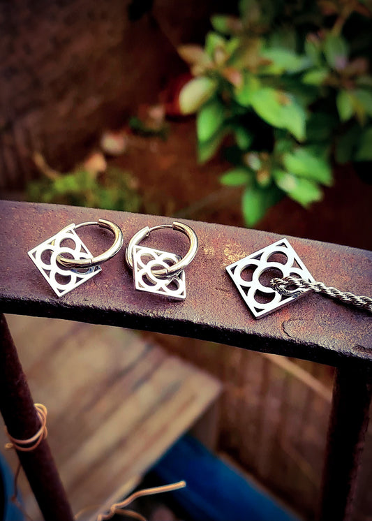 Conjunto con la Flor de Barcelona de acero inoxidable cuadrada para mujer. Sobre baranda de hierro.