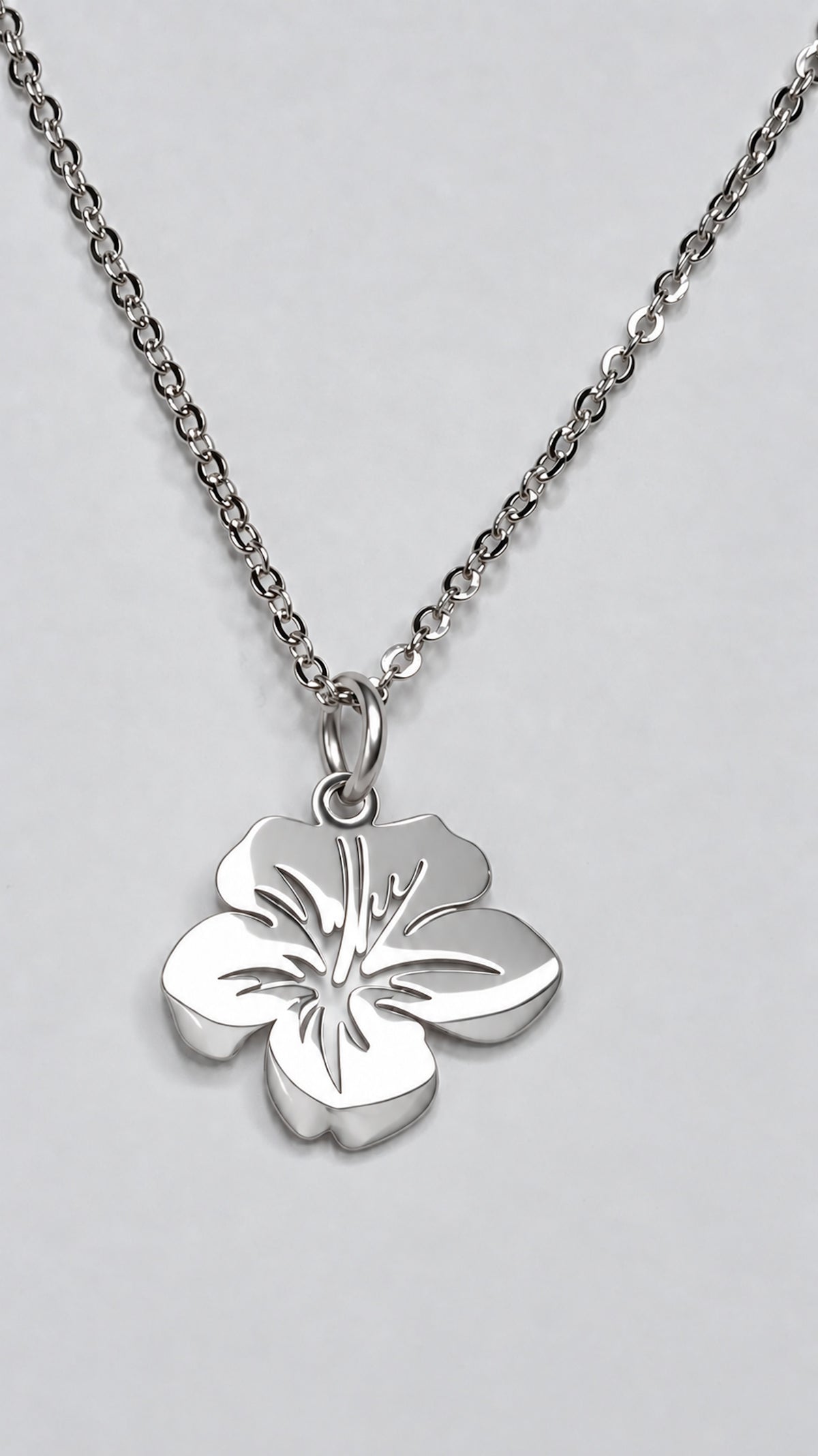 Colgante floral pequeño de acero inoxidable en acabado plateado con cadena.