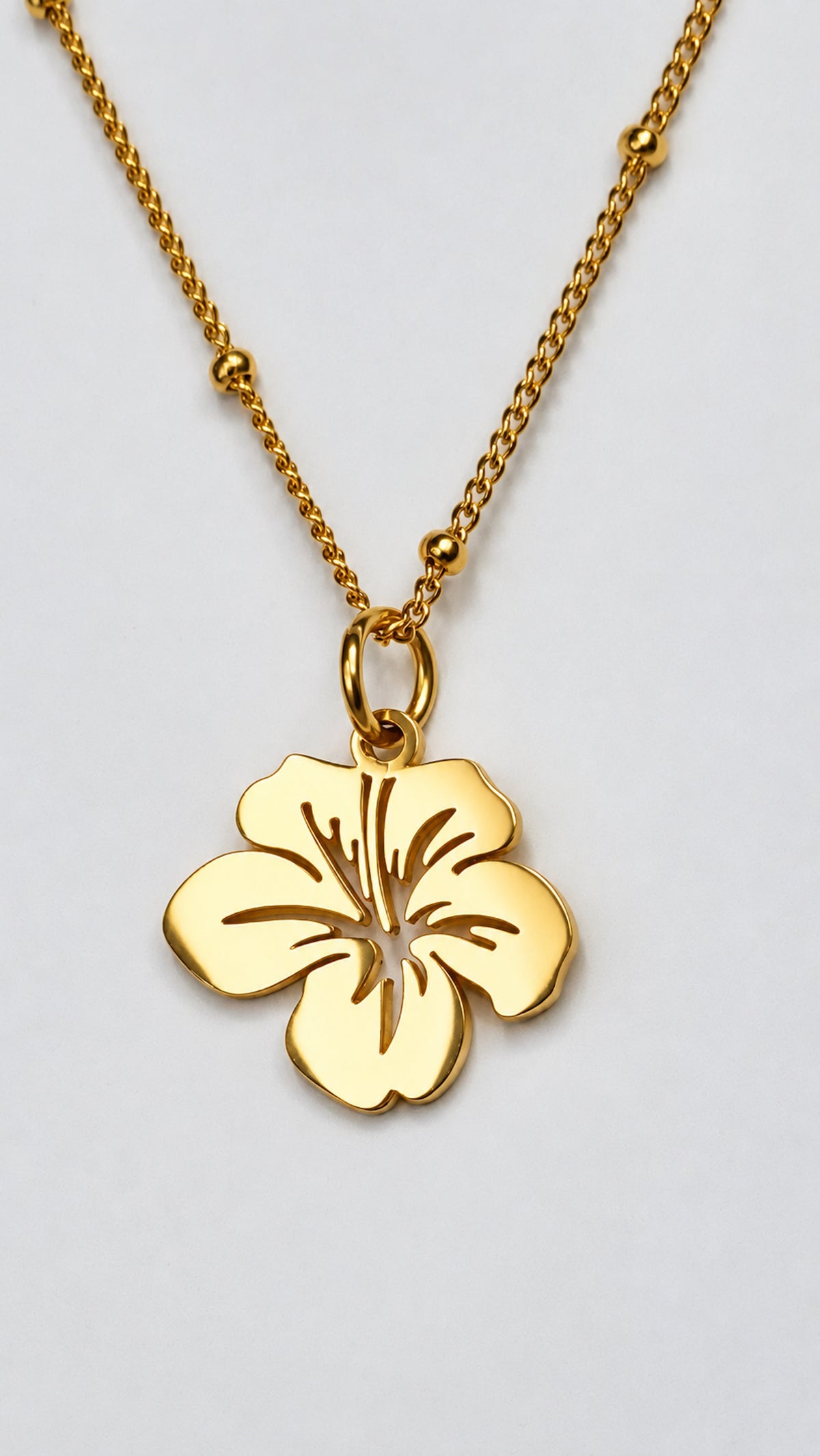 Colgante floral pequeño de acero inoxidable en acabado dorado con cadena.